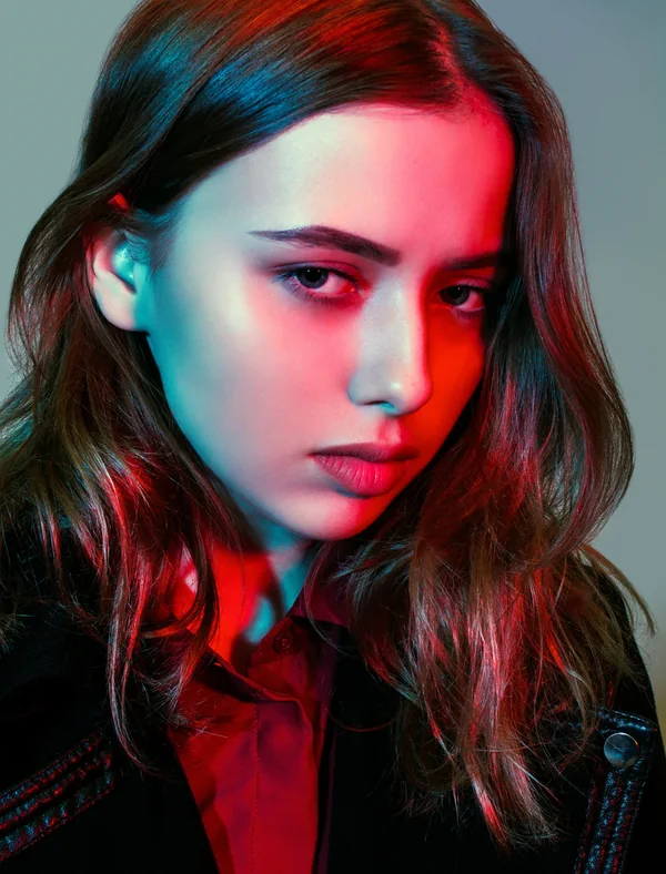 Editorial portrait under red and teal gel lighting after colour grading and tonal retouching